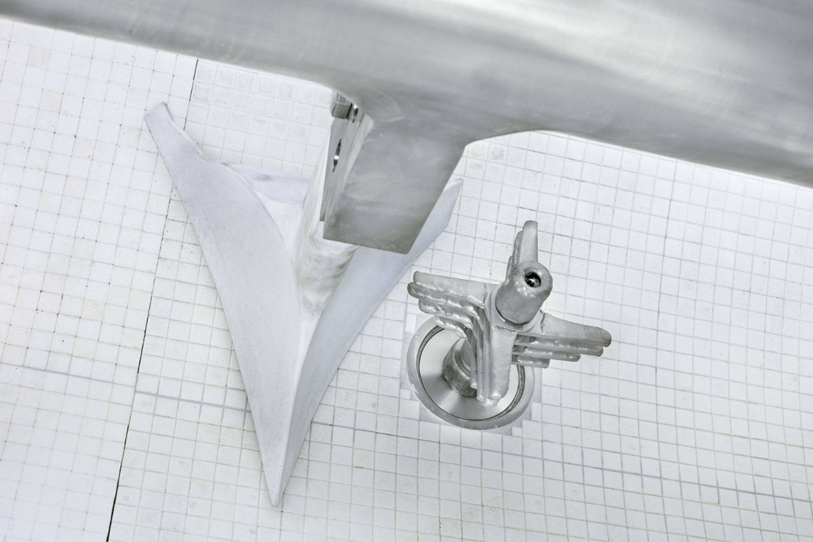 Metallkomponenten aus der Batterieherstellung auf einem weißen Gitteruntergrund.